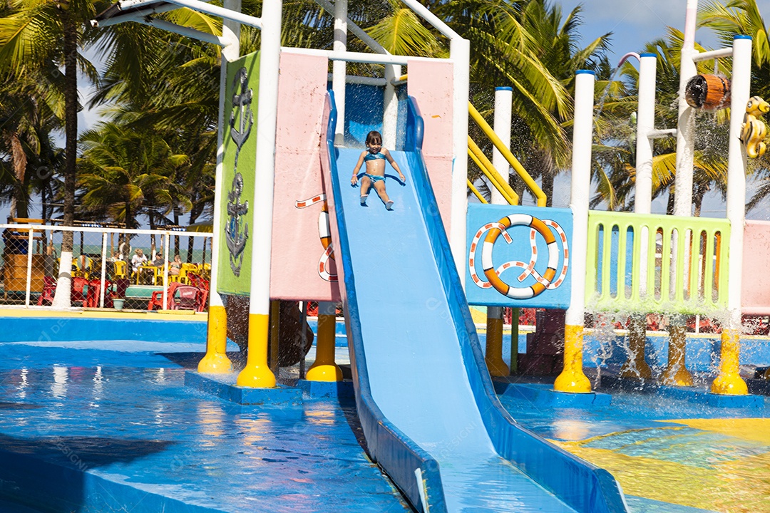Linda garotinha brincando no tobogã do parque de diversões