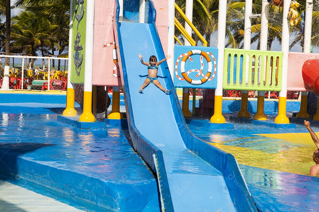 Linda garotinha brincando no tobogã do parque de diversões