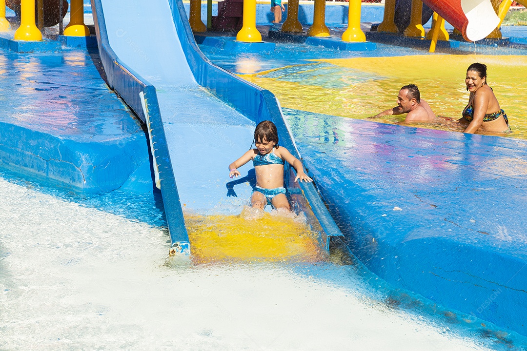 Linda garotinha brincando no tobogã do parque de diversões