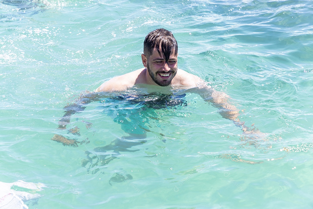 Homem sorridente mergulhando na praia