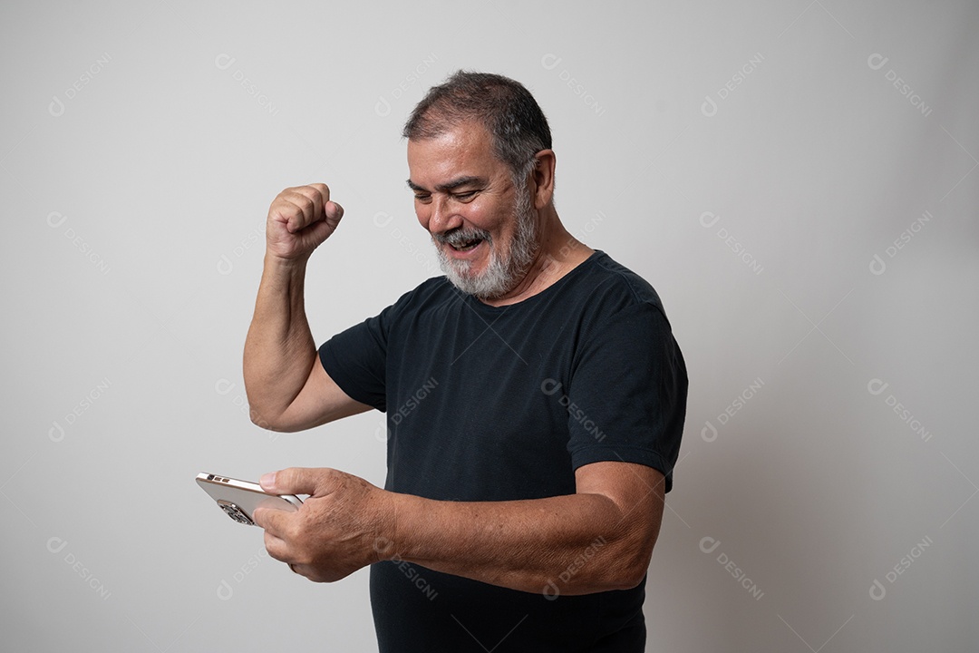 Homem barbudo maduro em roupas casuais, segurando o dispositivo de comunicação contra um fundo cinza.