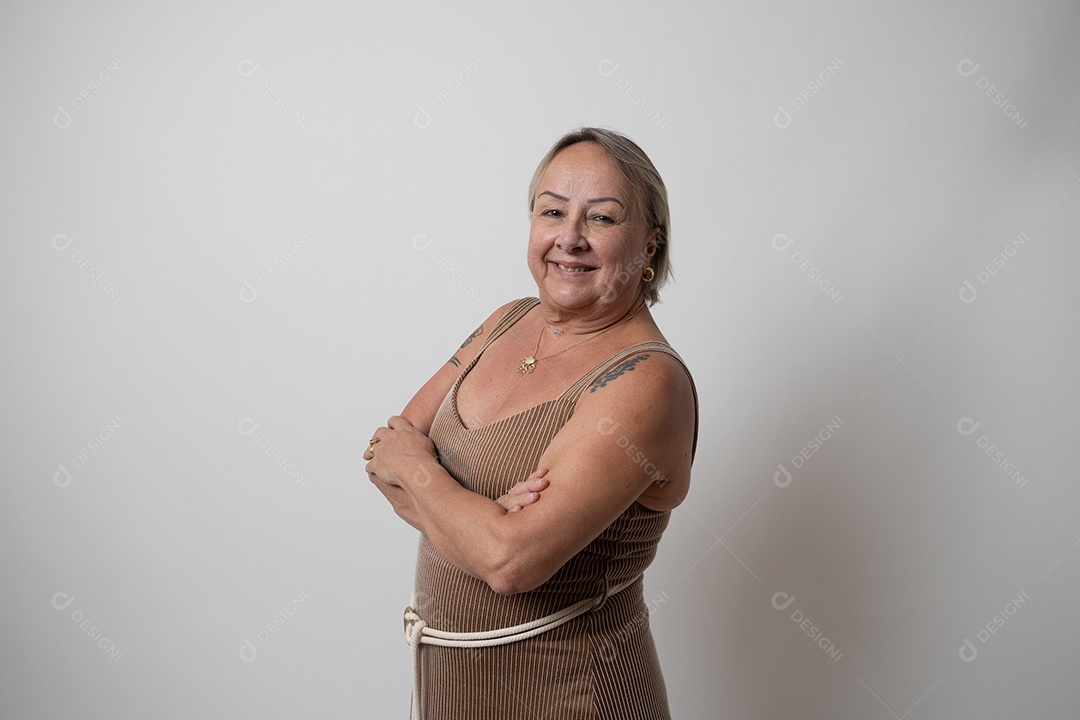 Mulher sênior alegre em vestido formal, sorrindo sozinha no estúdio.