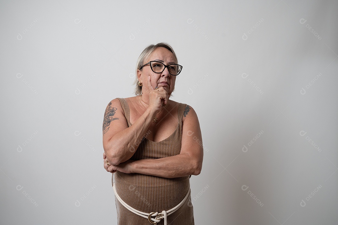 Mulher sênior alegre em vestido formal, sorrindo sozinha no estúdio.