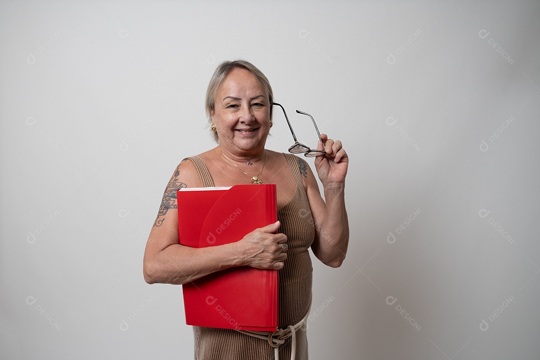 Mulher sênior alegre em vestido formal, sorrindo sozinha no estúdio.