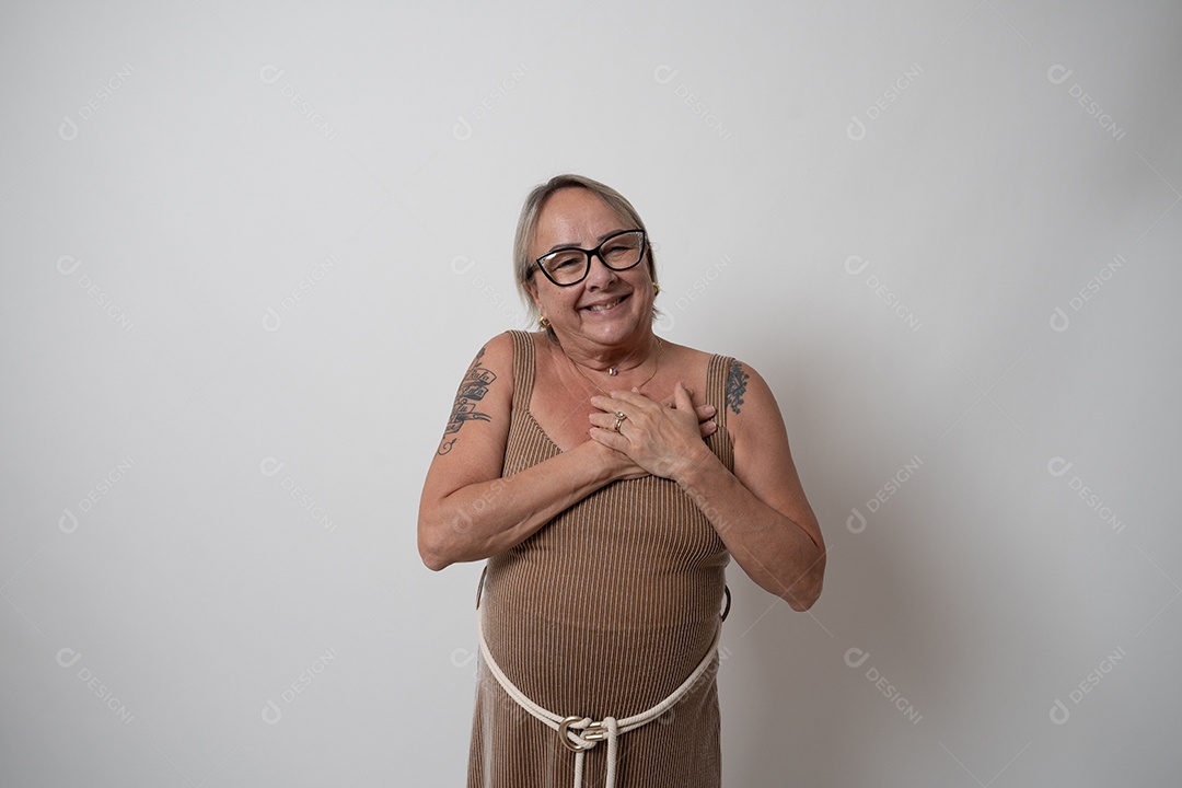 Mulher sênior alegre em vestido formal, sorrindo sozinha no estúdio.