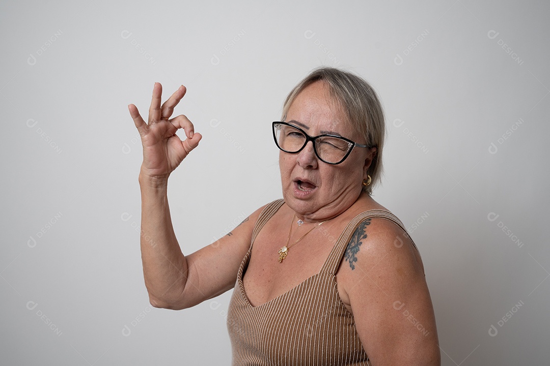 Mulher sênior alegre em vestido formal, sorrindo sozinha no estúdio.