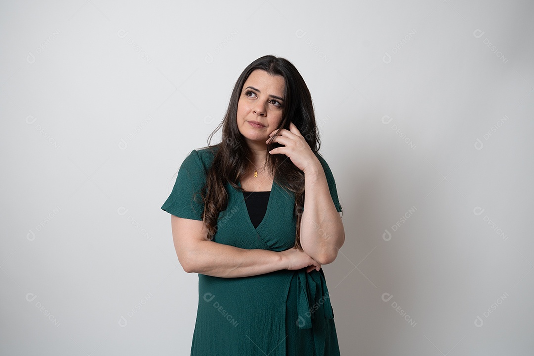 Mulher de cabelos castanhos em vestido elegante, posando para a câmera em estúdio.
