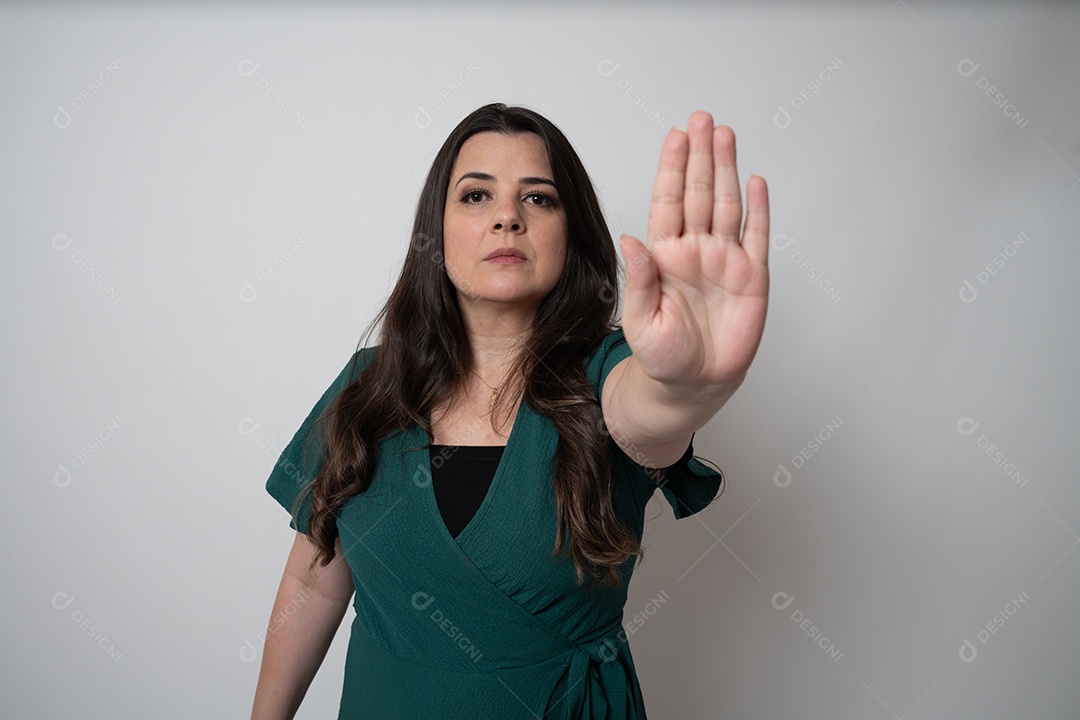 Mulher de cabelos castanhos em vestido elegante, posando para a câmera em estúdio.