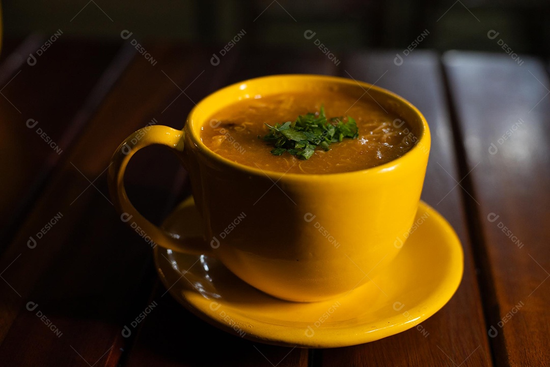 Xícara de sopa de lentilha sobre uma mesa de madeira