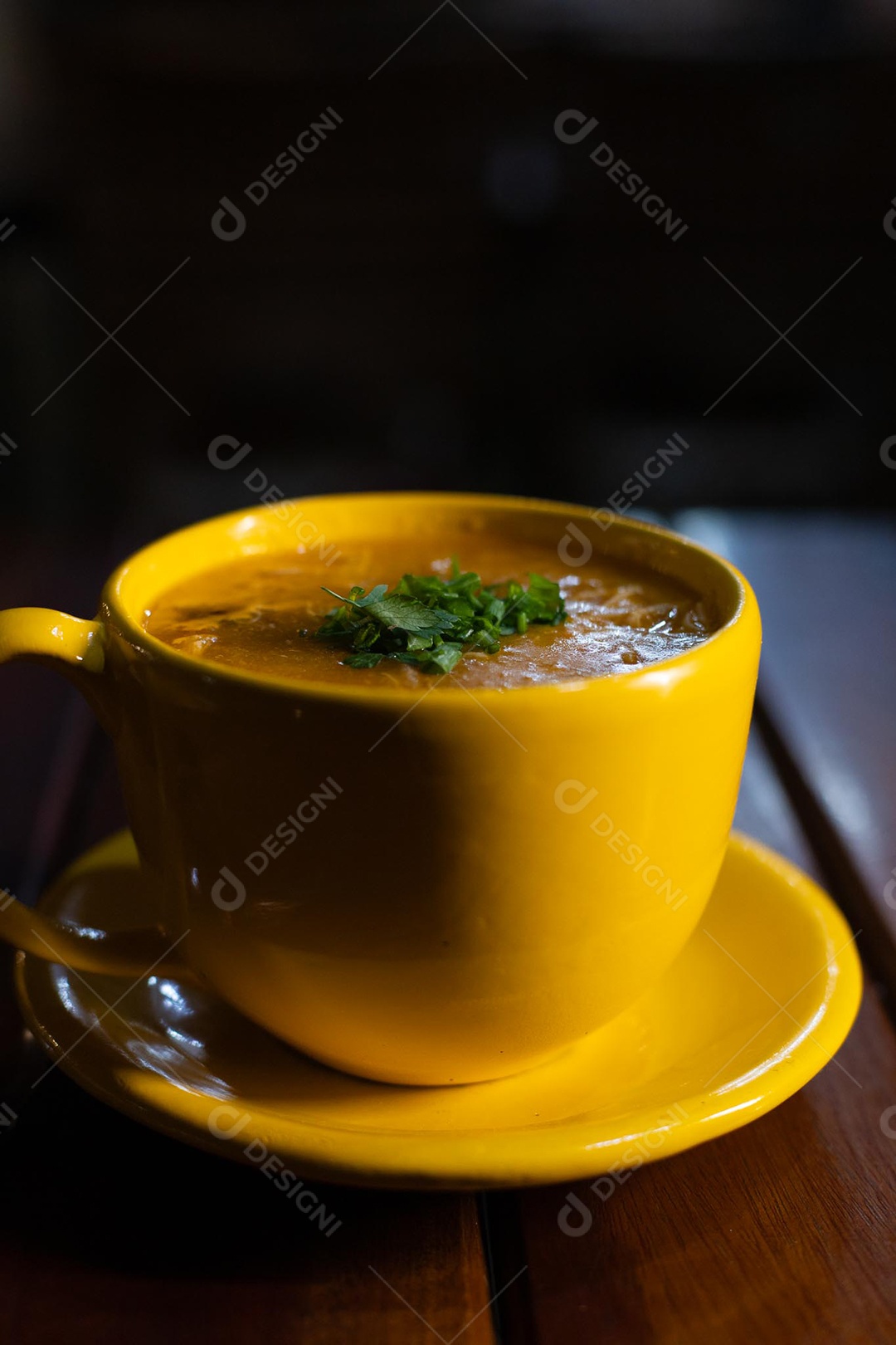 Xícara de sopa de lentilha sobre uma mesa de madeira