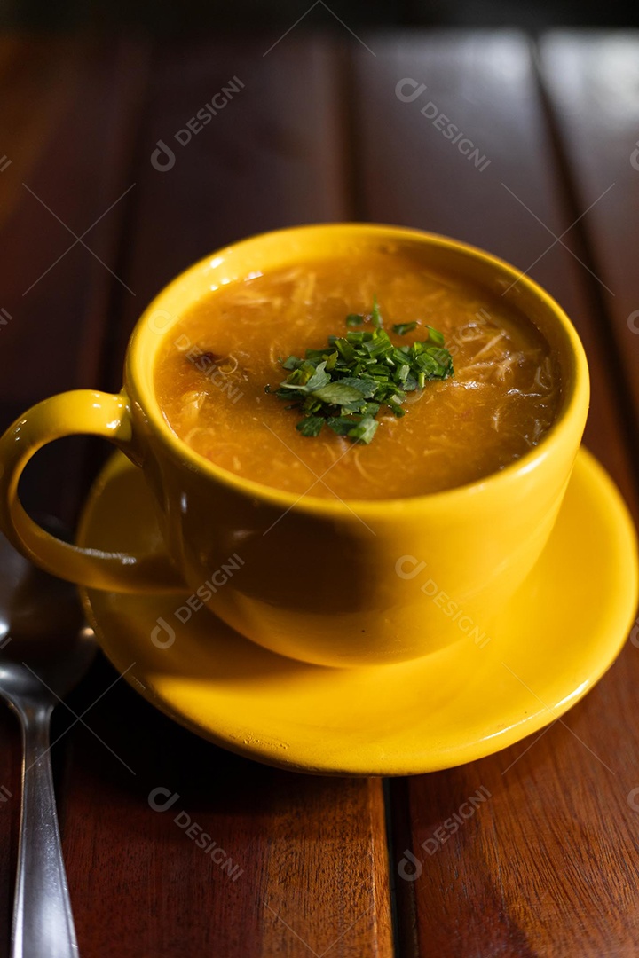 Xícara de sopa de lentilha sobre uma mesa de madeira