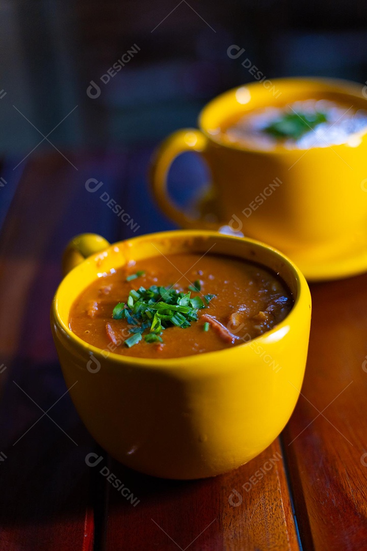 Xícara de sopa de lentilha sobre uma mesa de madeira