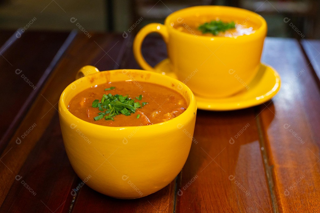 Xícara de sopa de lentilha sobre uma mesa de madeira