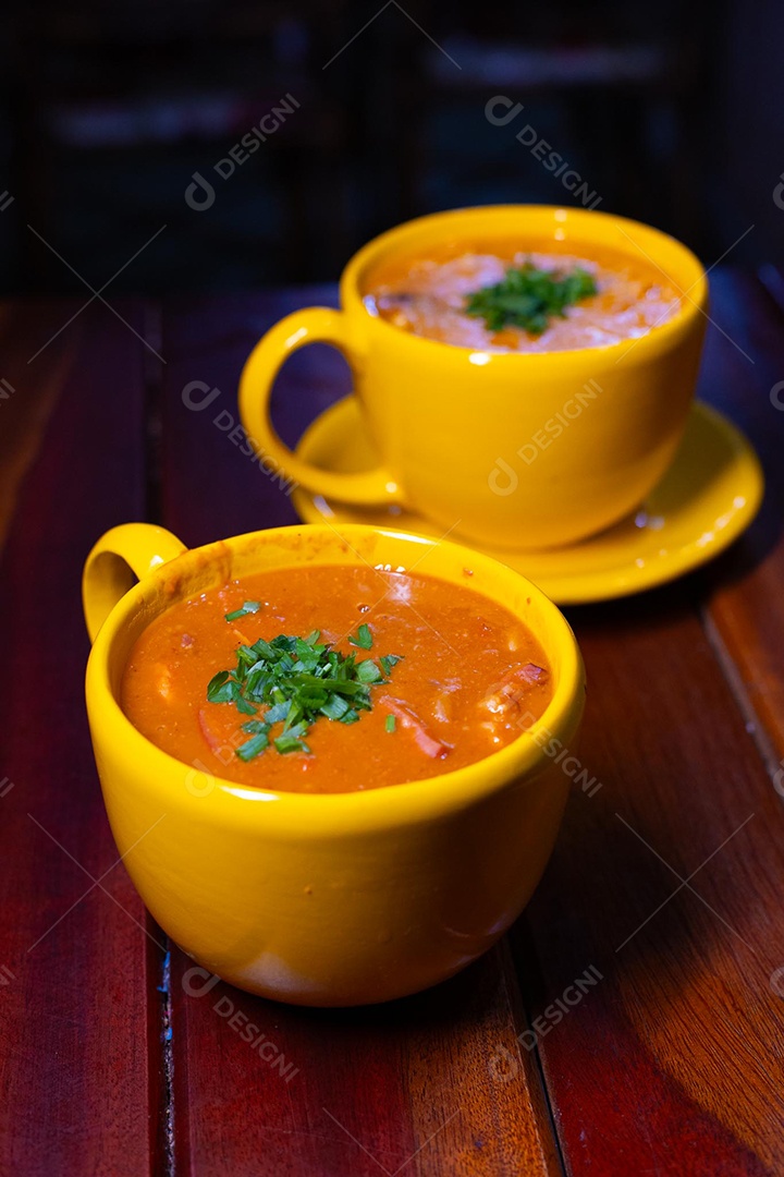 Xícara de sopa de lentilha sobre uma mesa de madeira