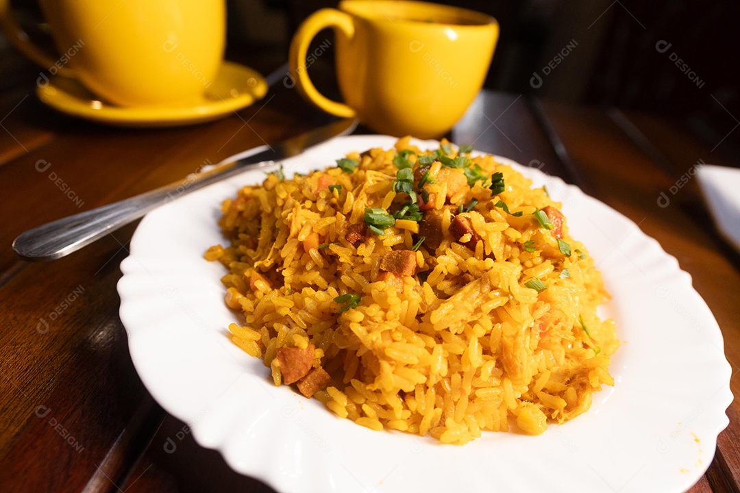 Um prato de galinhada sobre uma mesa de madeira