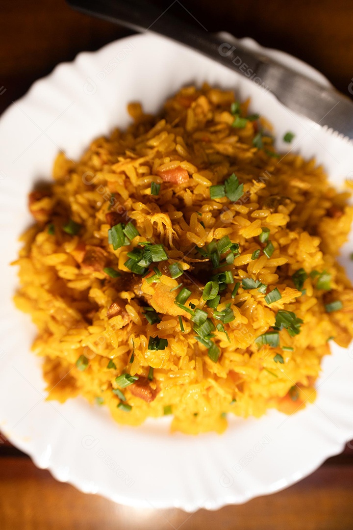 Um prato de galinhada sobre uma mesa de madeira