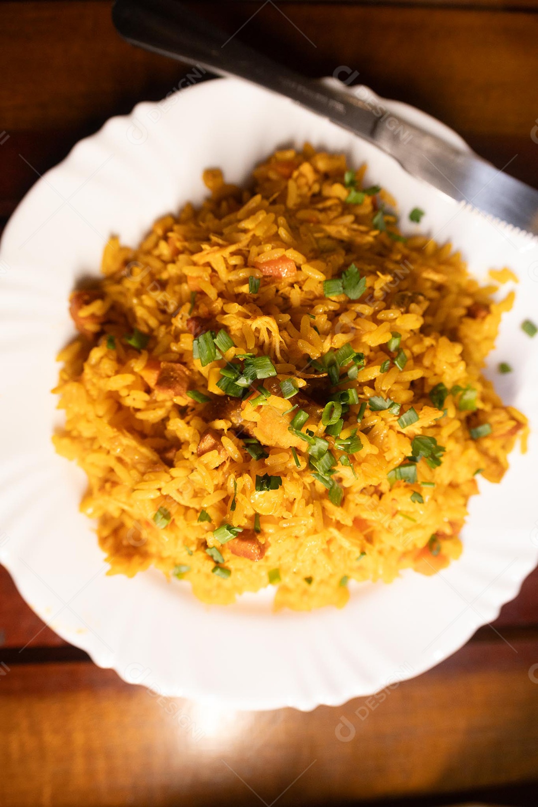 Um prato de galinhada sobre uma mesa de madeira