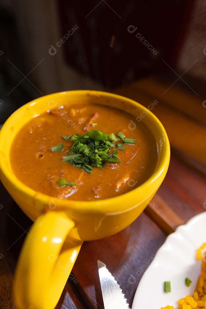 Xícara de sopa de lentilha sobre uma mesa de madeira