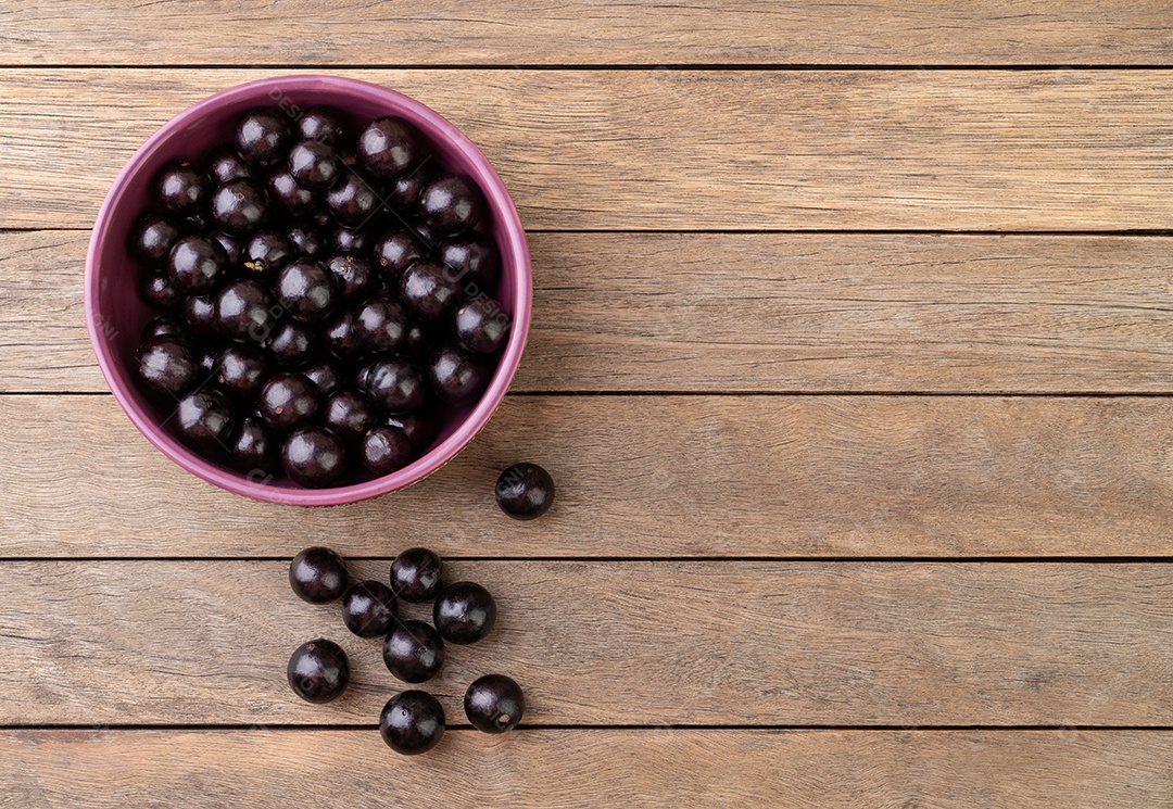 Jabuticabas em uma tigela sobre mesa de madeira com espaço de cópia.