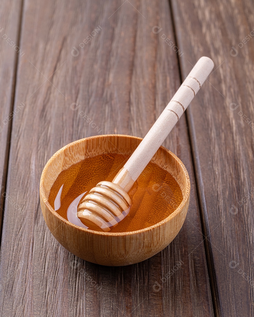 Mel em uma tigela pequena com concha de madeira e espaço para texto.