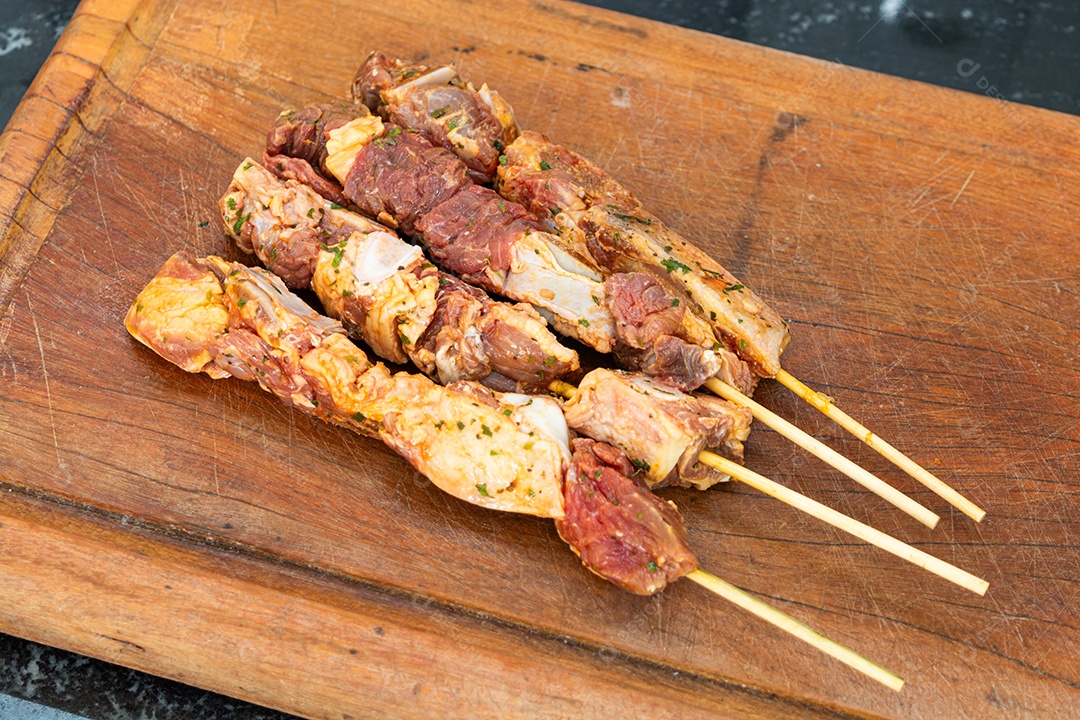 Espetinhos prontos sobre tábua de madeira