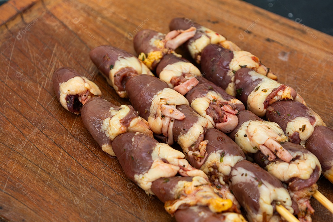 Espetinhos de coração de galinha sobre tábua de madeira