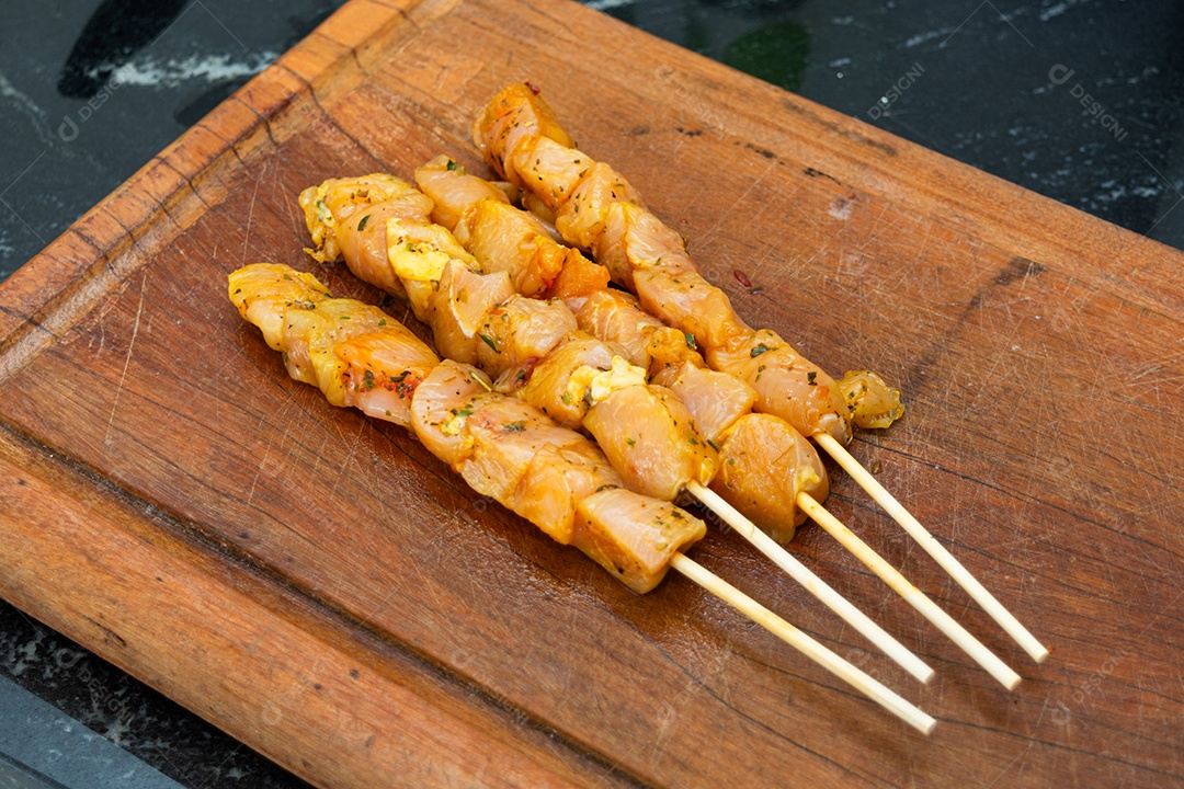Espetinhos de frango prontos sobre tábua de madeira
