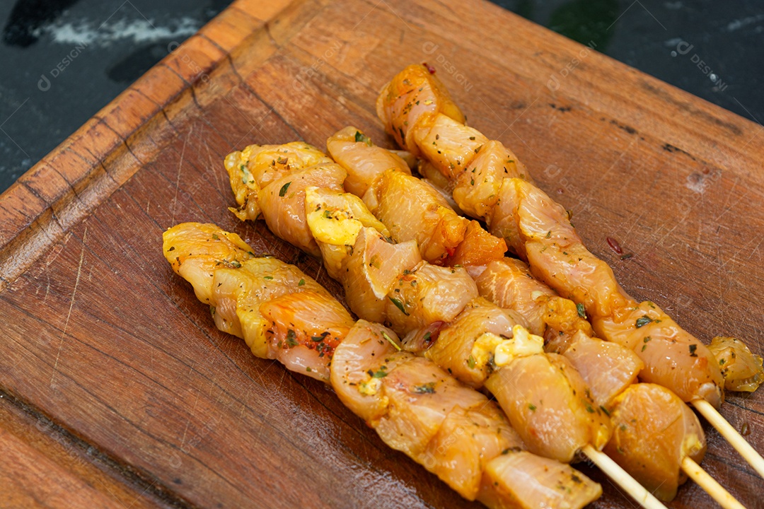 Espetinhos de frango prontos sobre tábua de madeira