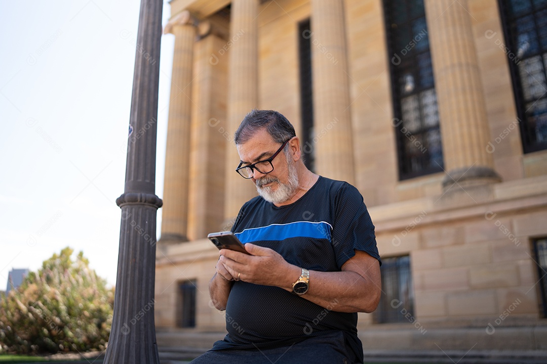 Homem adulto na cidade usando telefone celular com formação arquitetônica.