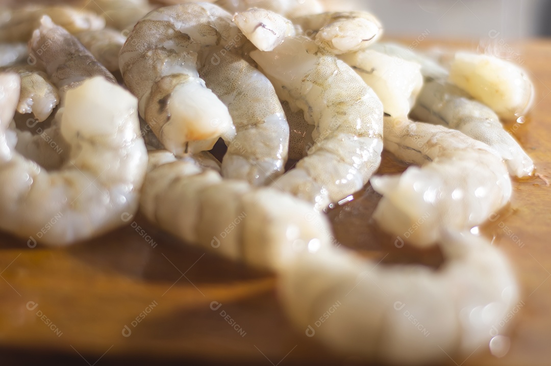 Camarões frescos em uma tábua de madeira com luz natural