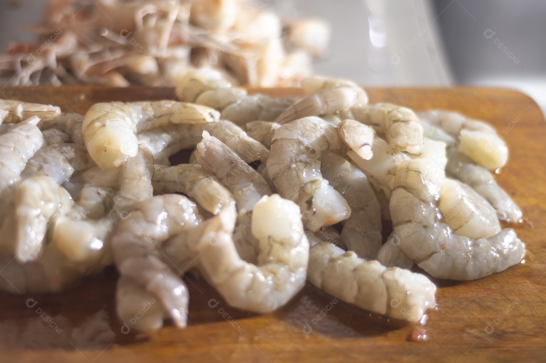 Camarões frescos em uma tábua de madeira com luz natural