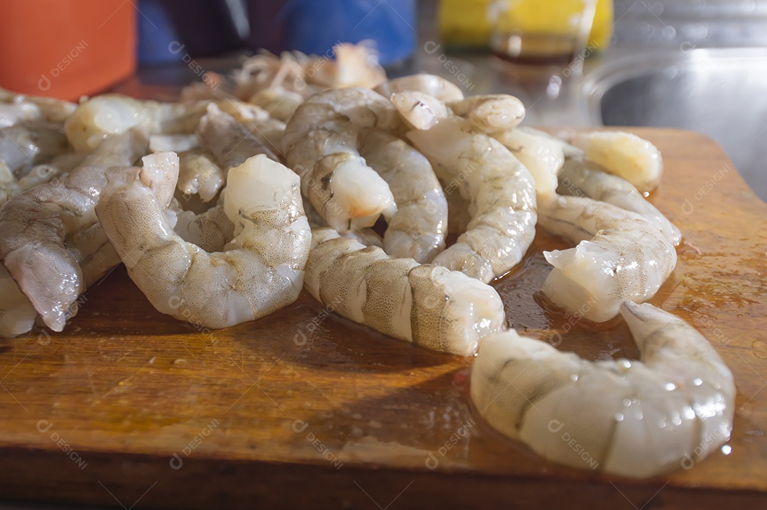 Camarões frescos em uma tábua de madeira com luz natural