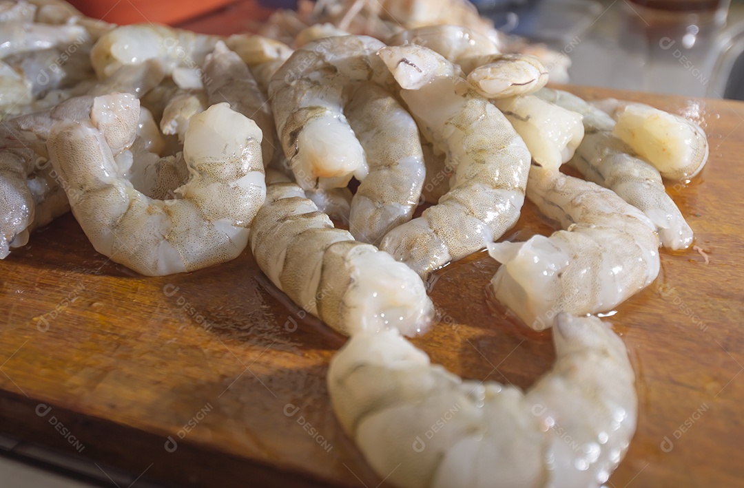 Camarões frescos em uma tábua de madeira com luz natural