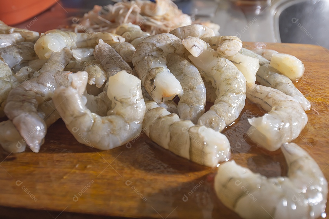 Camarões frescos em uma tábua de madeira com luz natural