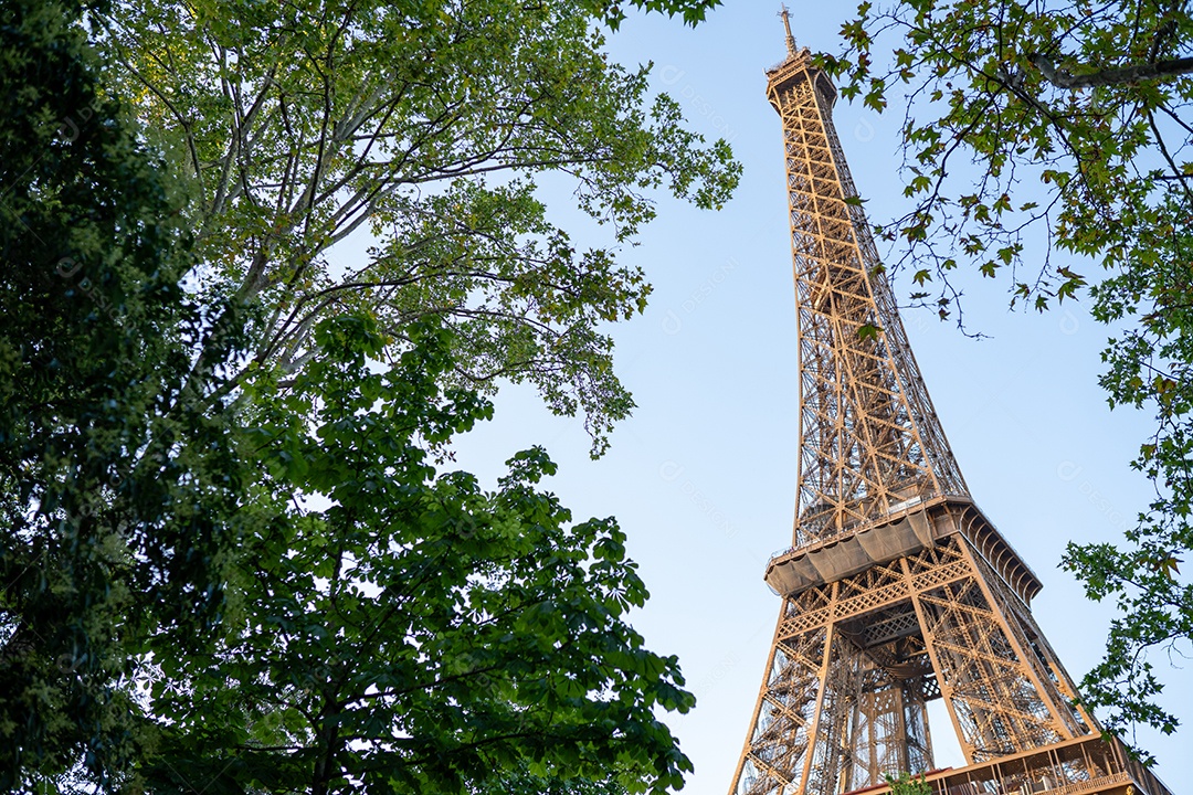 A Torre Eiffel vista através de árvores com um lindo céu de verão ao fundo, Paris, França
