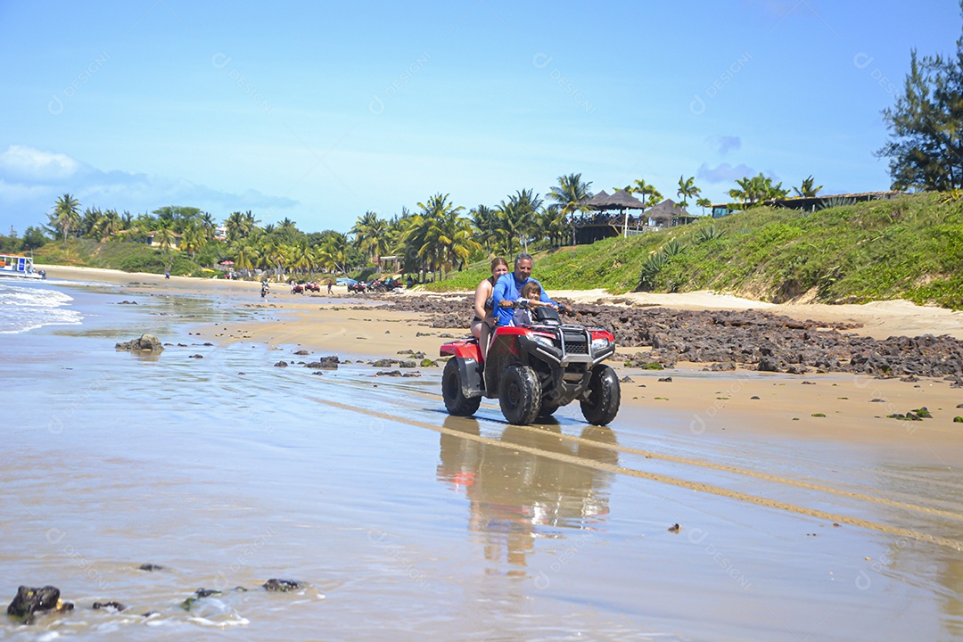 Família andando de quadriciclo pela praia
