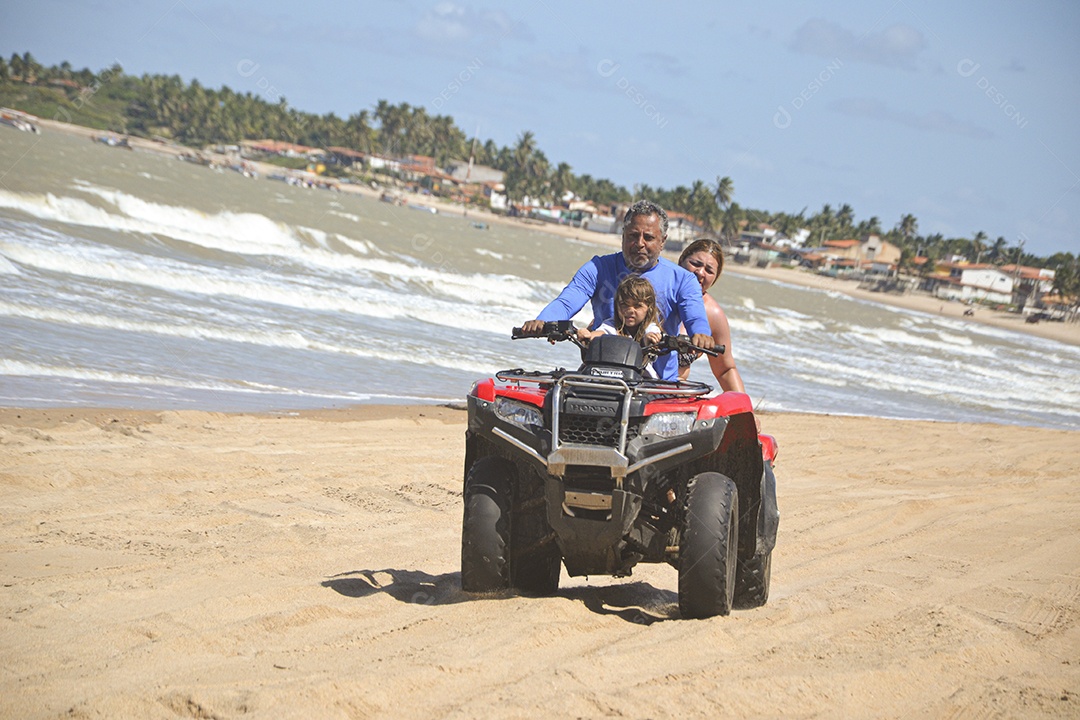 Família andando de quadriciclo pela praia