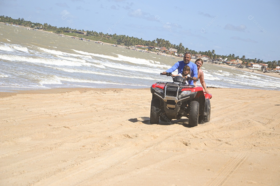 Família andando de quadriciclo pela praia