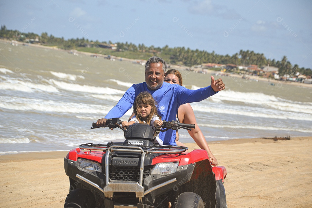 Família andando de quadriciclo pela praia