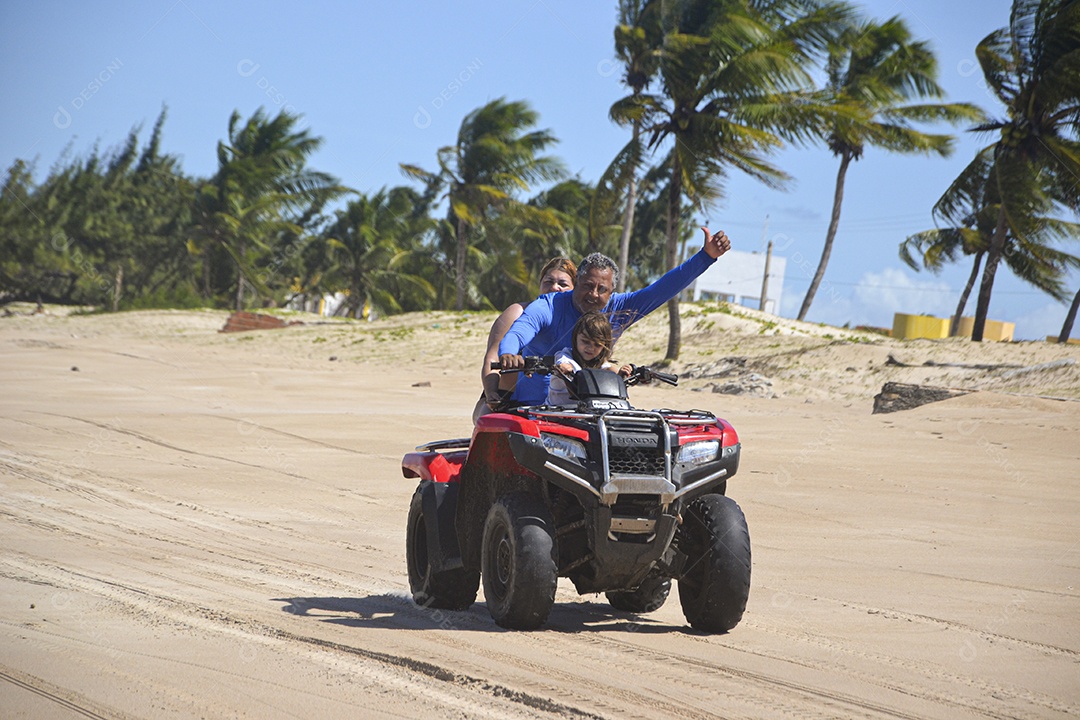 Família andando de quadriciclo pela praia