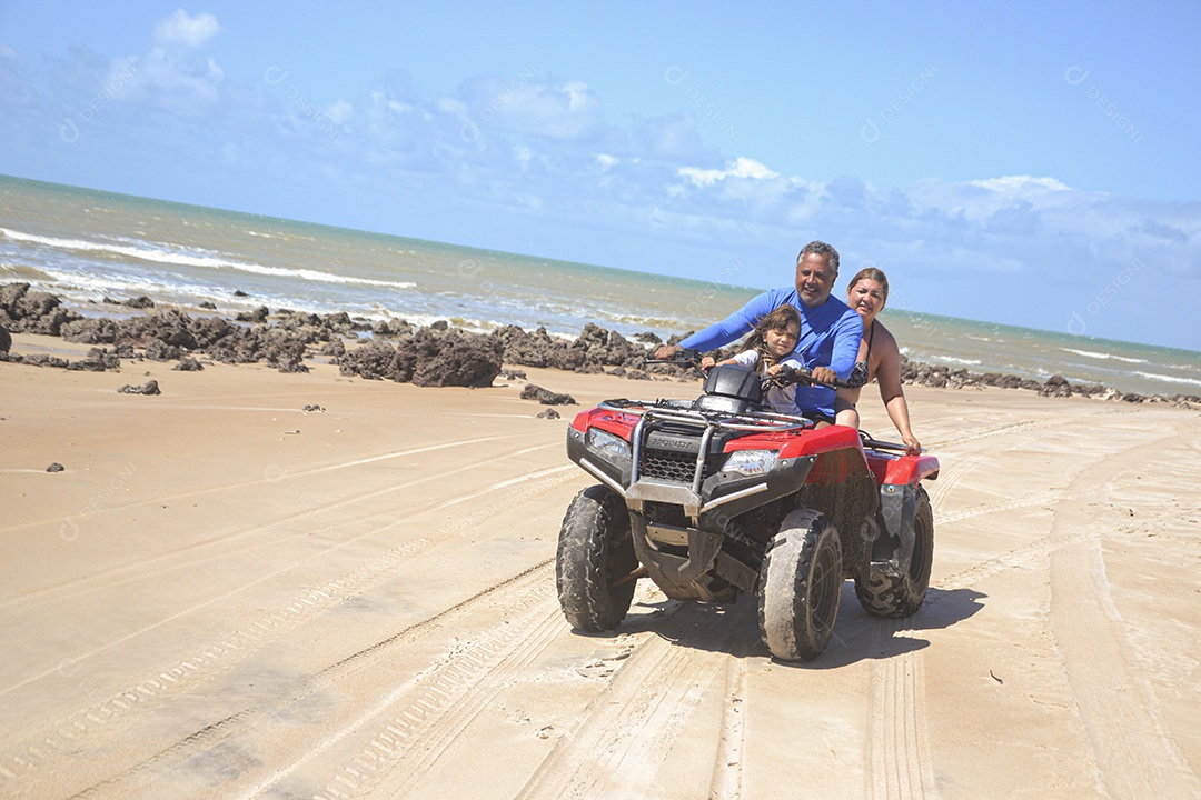 Família andando de quadriciclo pela praia