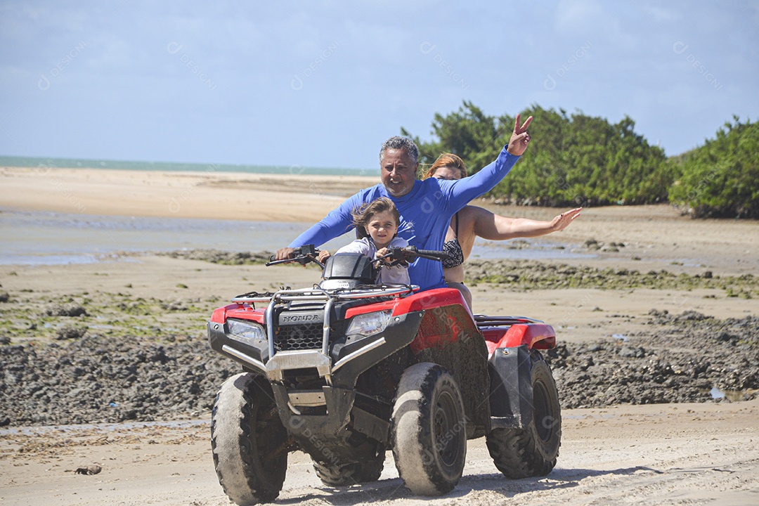 Família andando de quadriciclo pela praia