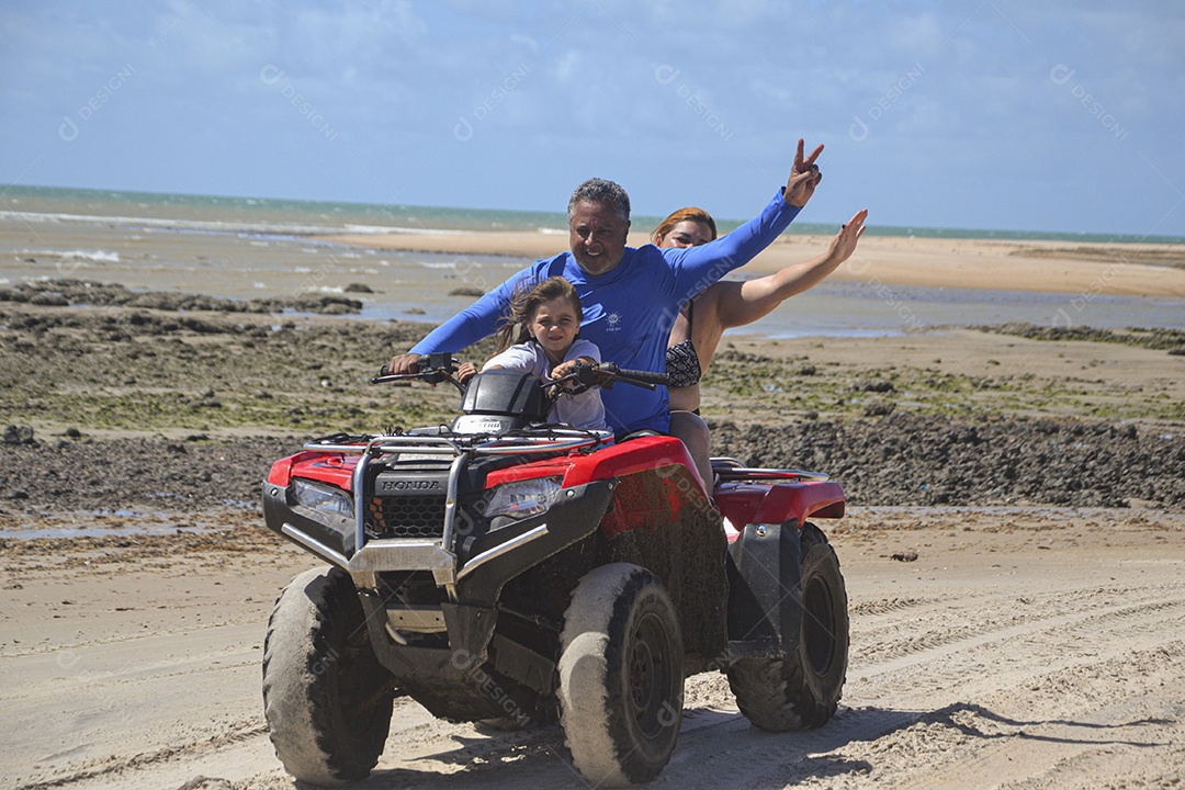 Família andando de quadriciclo pela praia