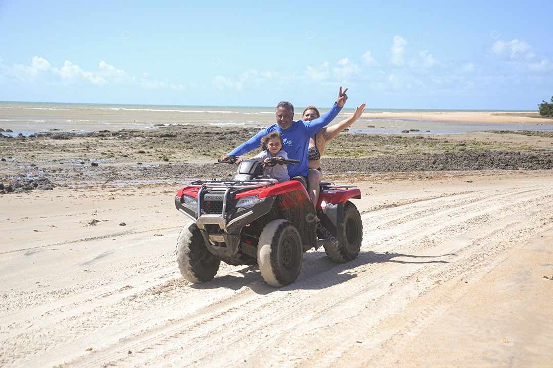 Família andando de quadriciclo pela praia