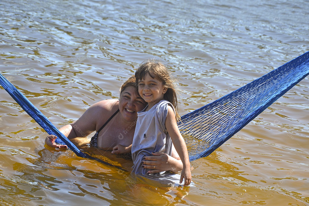 Mulher e menininha sorridentes curtindo a praia
