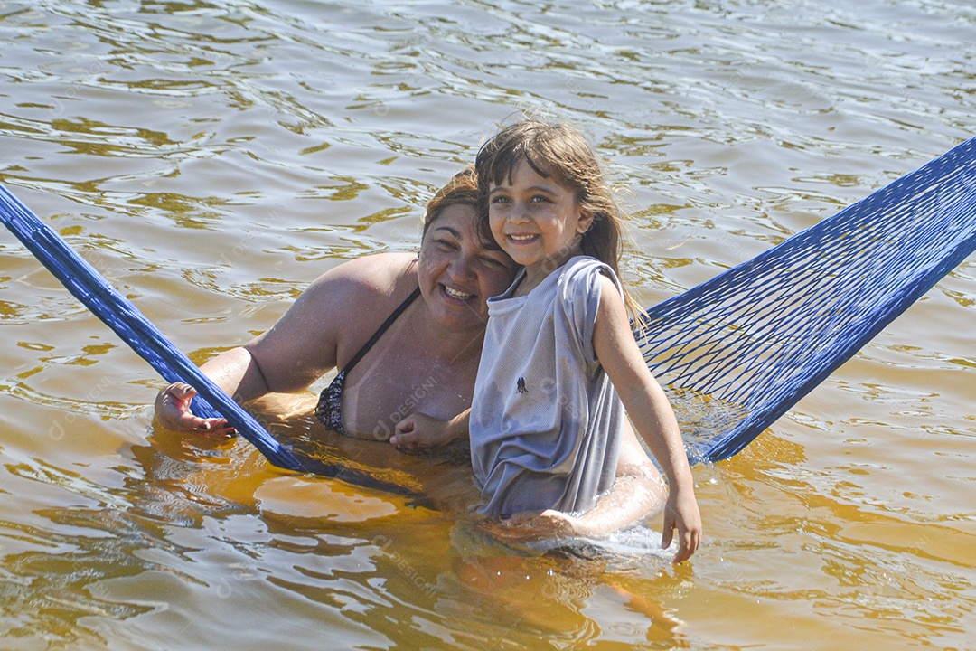 Mulher e menininha sorridentes curtindo a praia