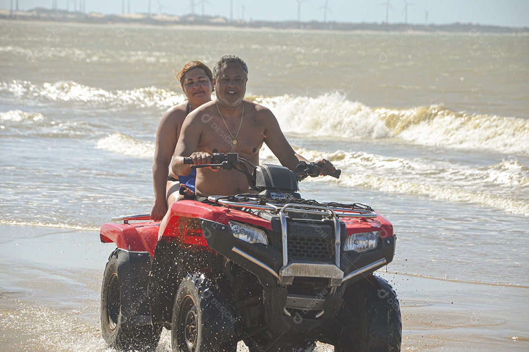 Casal feliz andando de quadriciclo na praia