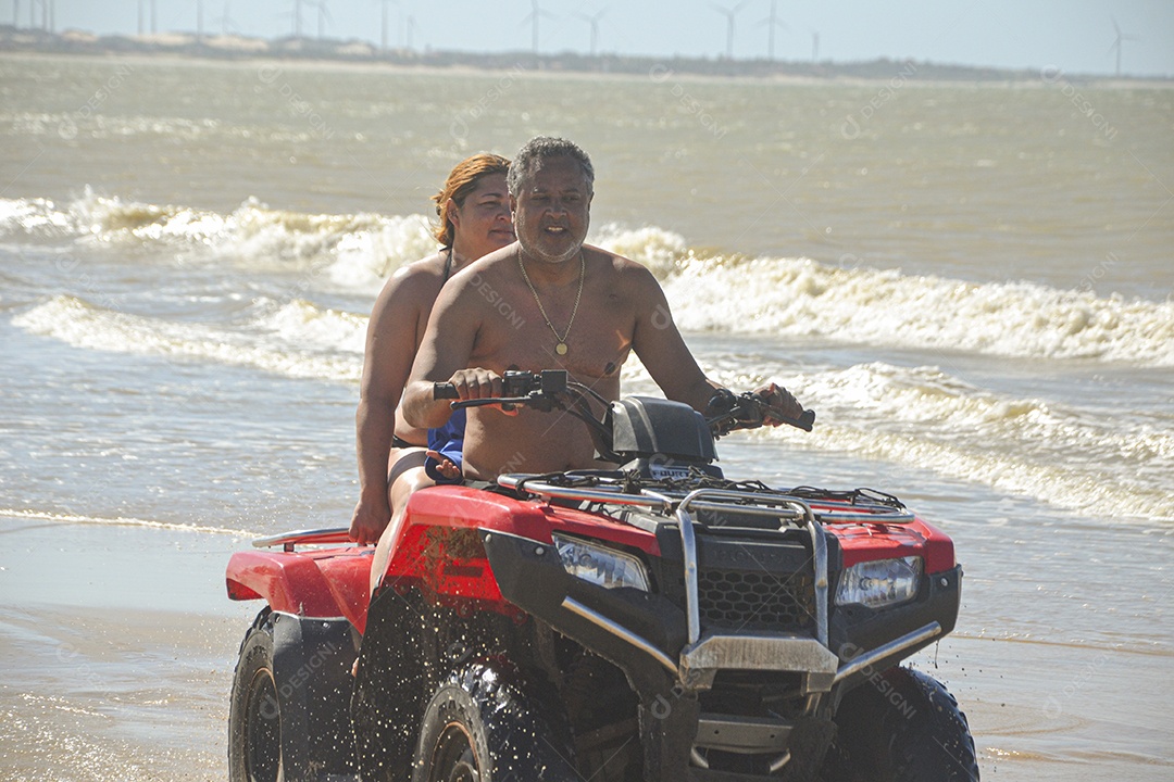 Casal feliz andando de quadriciclo na praia