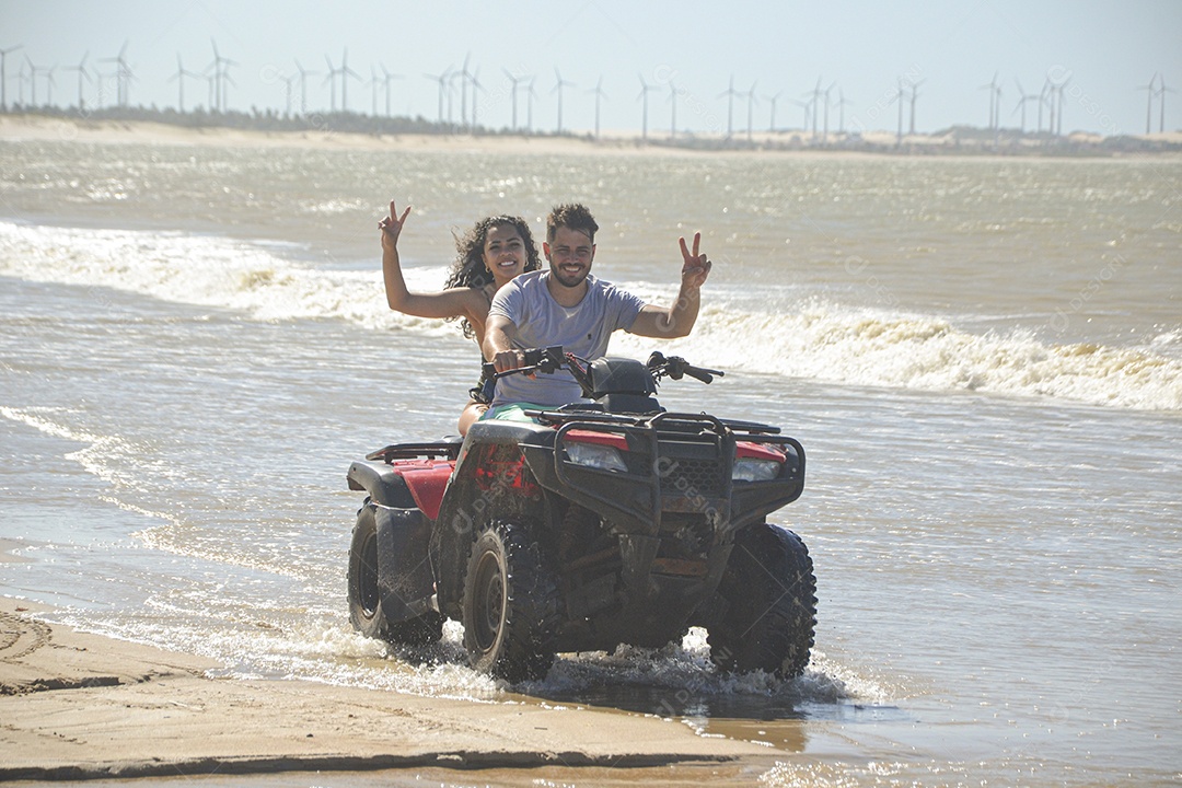 Casal feliz andando de quadriciclo na praia