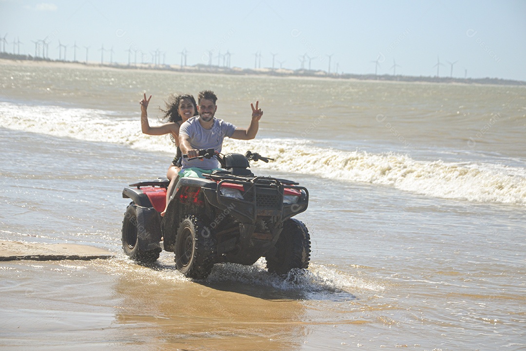 Casal feliz andando de quadriciclo na praia